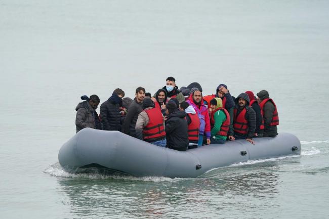 A dinghy carrying people thought to be migrants, arrives on a beach in Dungeness, Kent