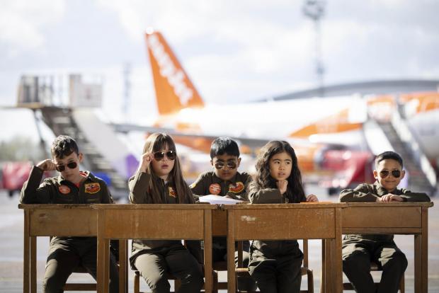 Surrey Comet: Sam Bennett, aged 12, Olivia Joohee-Riddington, aged 9, Arjun Giri, aged 9, Rei Diec, aged 7 and Rico Jeerasinghe, aged 9 during filming of a parody of the movie Top Gun at Luton airport as part of easyJet's nextGen recruitment campaign. Credit: PA/easyJet
