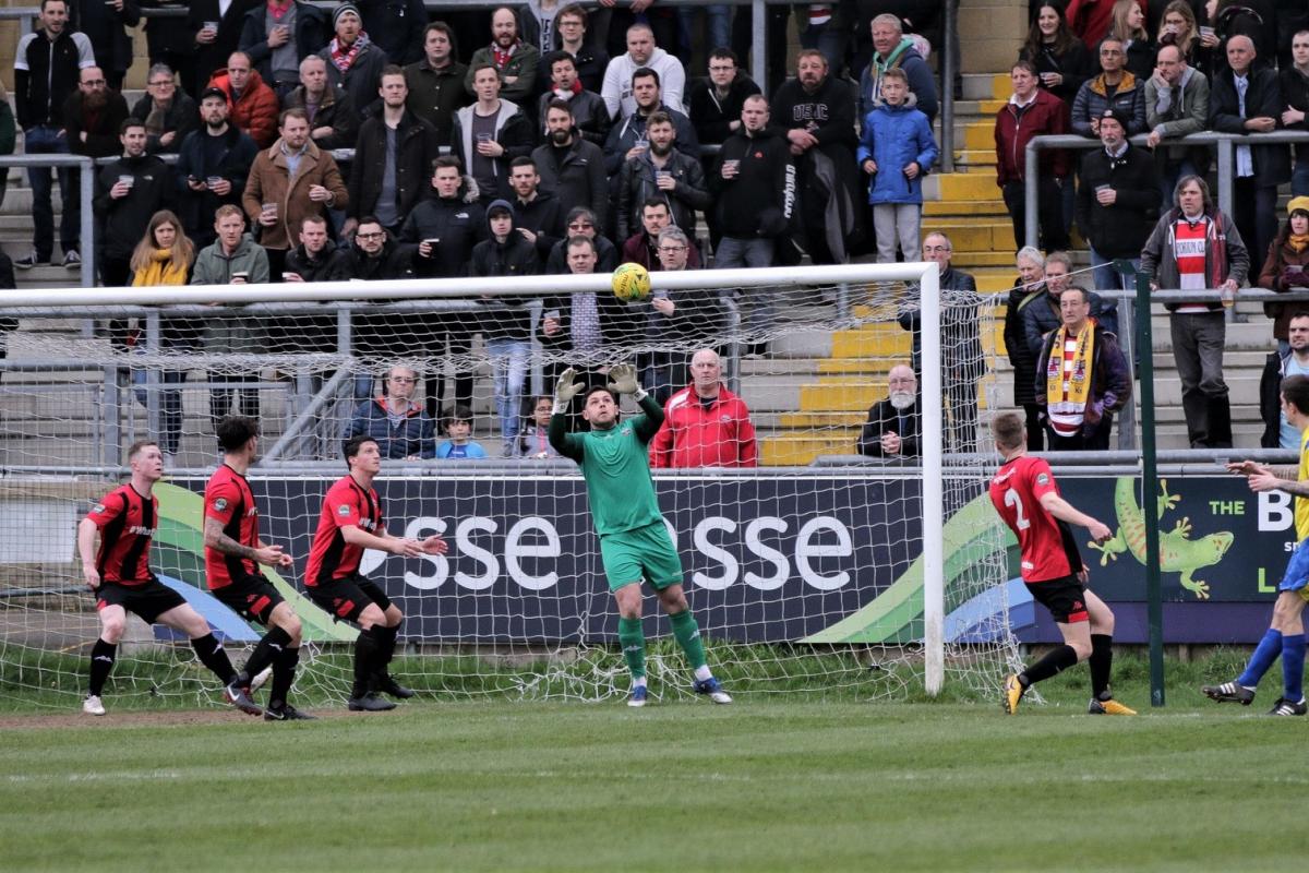 Dean Inman's header is saved at Lewes as Kingstonian's sizeable away support looks on. Pic: James Boyes.
